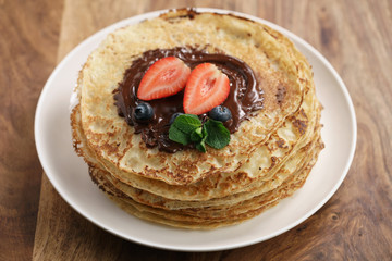 fresh blinis or crepes with melted dark chocolate and berries, shallow focus