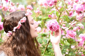 Naklejka premium Girl smells the roses in the garden