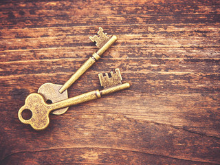 a set of old skeleton keys on a wooden background toned with a retro filter