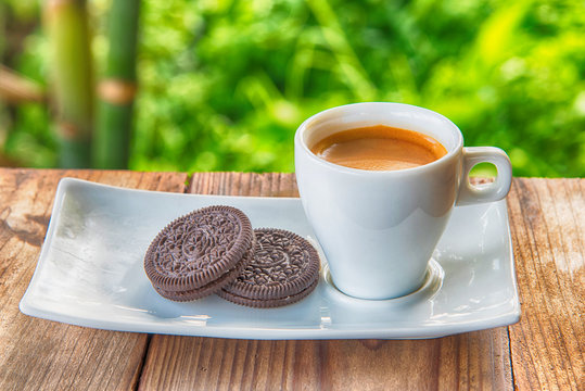 Cup of coffee with cookie on table