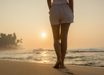 Beach travel - woman walking on sand beach leaving footprints in