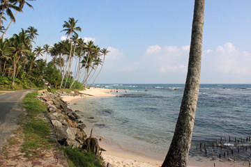 Küste mit Straße, Palmen, Strand und einheimischen Badenden am Indischen Ozean zwischen Mirissa und Matara in Sri Lanka