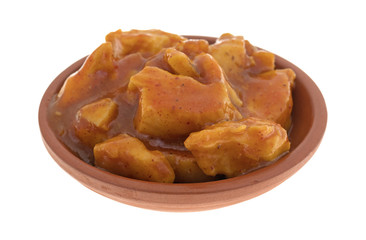 A small bowl filled with chunks of chicken in barbecue sauce isolated on a white background.
