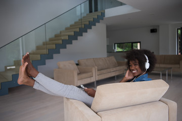 African american woman at home in chair with tablet and head pho