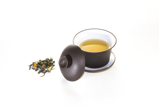 snuff cup with green, flower tea, gaivan and a tea cup on a whit