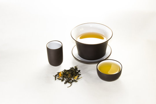 snuff cup with green, flower tea, gaivan and a tea cup on a whit