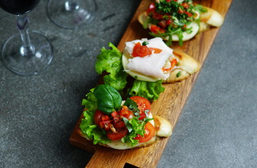 Italian bruschetta with roasted tomatoes, mozzarella cheese and herbs on a cutting board 