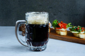 Cold dark beer in a glass and and Italian bruschetta on gray background 