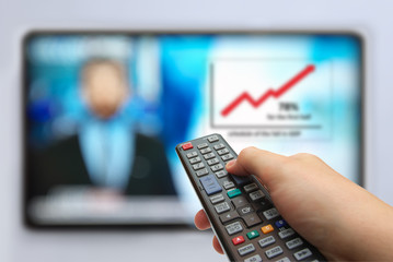 Man hand switches TV channels. Remote control in hand and TV