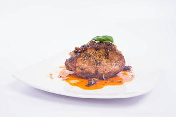 Roast pork decorated with basil on a white plate