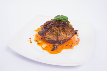 Roast pork decorated with basil on a white plate