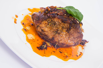 Roast pork decorated with basil on a white plate