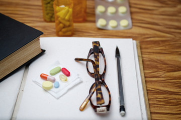 Open blank journal, pair of readers and medicine tablets suggesting the concept of memory loss