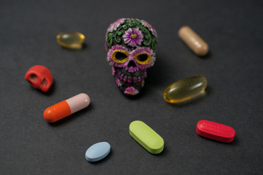 Calavera surrounded by pills on black background,  communicating the concept that drugs can be dangerous