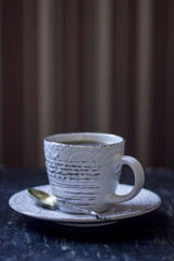A cup of coffee together with a delicious slice of a chocolate cake on a white and dark worn out background.