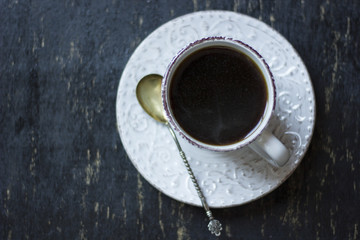 A cup of coffee together with a delicious slice of a chocolate cake on a white and dark worn out background.
