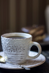 A cup of coffee together with a delicious slice of a chocolate cake on a white and dark worn out background.