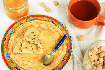 Plate with thin pancakes and honey.