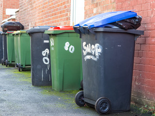 Row of Wheelie Bins in alley with rubbish overflowing