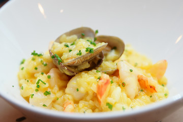 Saffron risotto with shellfish in white plate, close-up