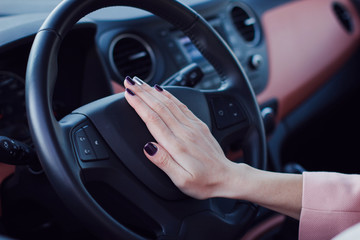 Woman push the button on a steering wheel in car