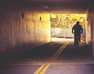  a bicyclist riding through a dark tunnel during summer
