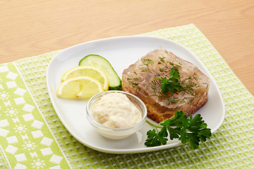 Aspic of beef on white plate with lemon, cucumber, horseradish and parsley