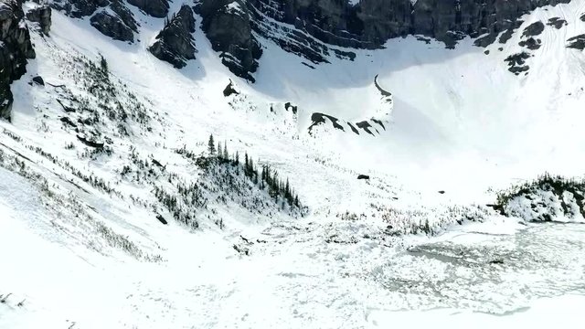 Aerial: Flying over frozen lake and avalanche debris