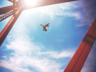 a boy jumping off an old train trestle bridge into a river toned with a retro instagram filter