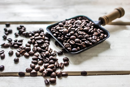 Coffee beans scattered on  rustic wood background. Arabica seeds heap at wooden table with copy space.