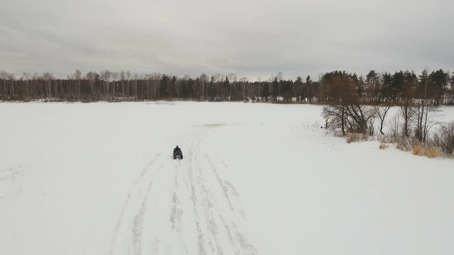 ATV race on the snow. Aerial view: Rider driving in the quadbike race. Man riding ATV in sand in protective clothing and a helmet. Racer rides a quad motorbike in the cross racing. Quadrocycle on the