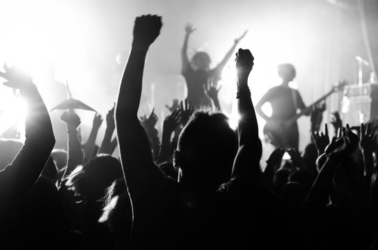 silhouettes of people at a concert in front of the scene in bright light