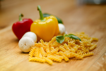 fresh vegetables and pasta lying on a wooden table.