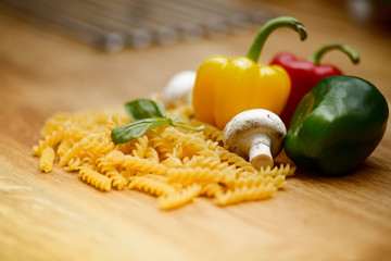 fresh vegetables and pasta lying on a wooden table.