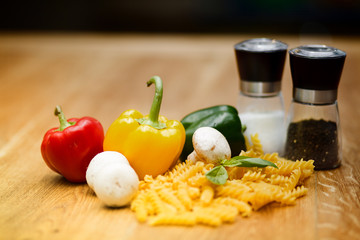fresh vegetables and pasta lying on a wooden table.