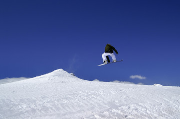 Snowboarder jump in terrain park at ski resort on sun winter day