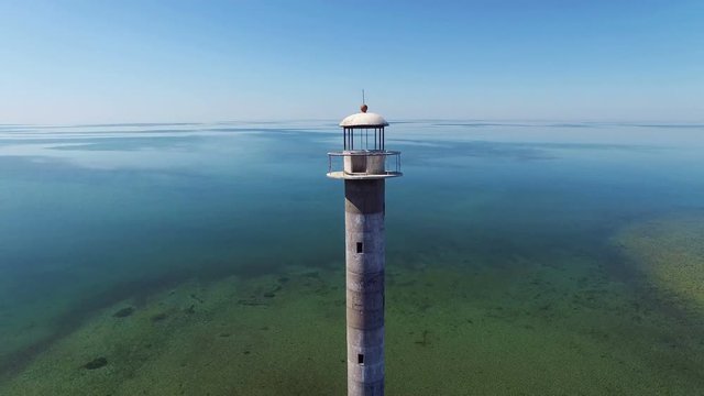 4K. Flight and takeoff over old lighthouse standing in the sea, aerial view. Estonia, Saaremaa island - Kiipsaare tuletorn.