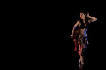 woman athlete in the Amazon costume with fur and skins posing on a black background in the scenic...
