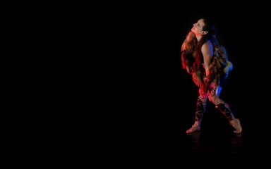 woman athlete in the Amazon costume with fur and skins posing on a black background in the scenic...