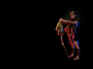 woman athlete in the Amazon costume with fur and skins posing on a black background in the scenic...