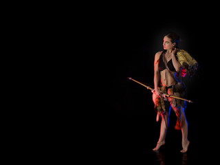 woman athlete in the Amazon costume with fur and skins posing on a black background in the scenic...