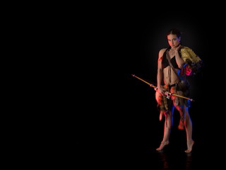woman athlete in the Amazon costume posing on a black background in the scenic red and blue light.