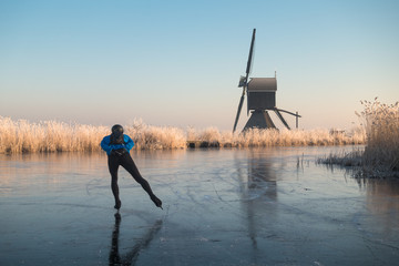 Ice skating past frosted reeds and a windmill