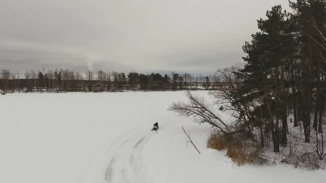 Man driving snowmobile in snowyfield. Snowmobile races. Man on a snowmobile. Racer on a snowmobile. Winter extreme sports. 4K video, drone footage.