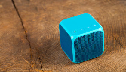 Blue bluetooth speaker cube on wood background