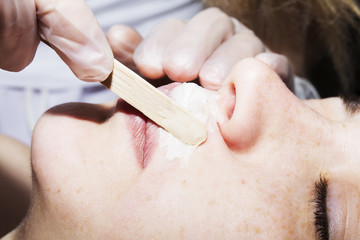 Depilation with hot wax mustache in the beauty salon. 
