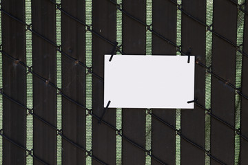 Blank white sign attached to backlit brown fence. Copy space.