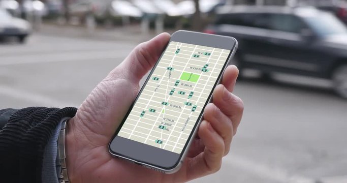 A man uses his smartphone to observe ride sharing traffic patterns on an interactive map in a city.  	