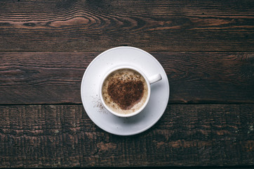 White coffee cup with heart shape on dark wooden background