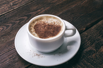 White coffee cup with heart shape on dark wooden background